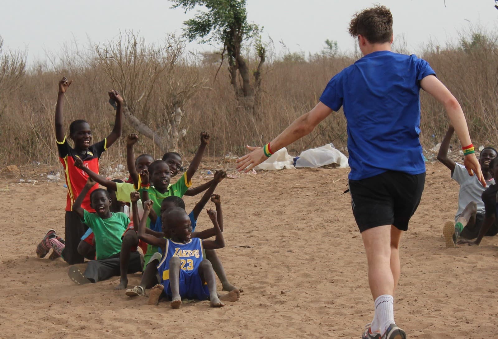 Young players competing for the ball on a sandy pitch